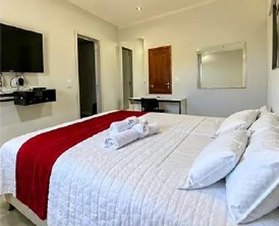 Cama de casal arrumada com toalhas e manta vermelha